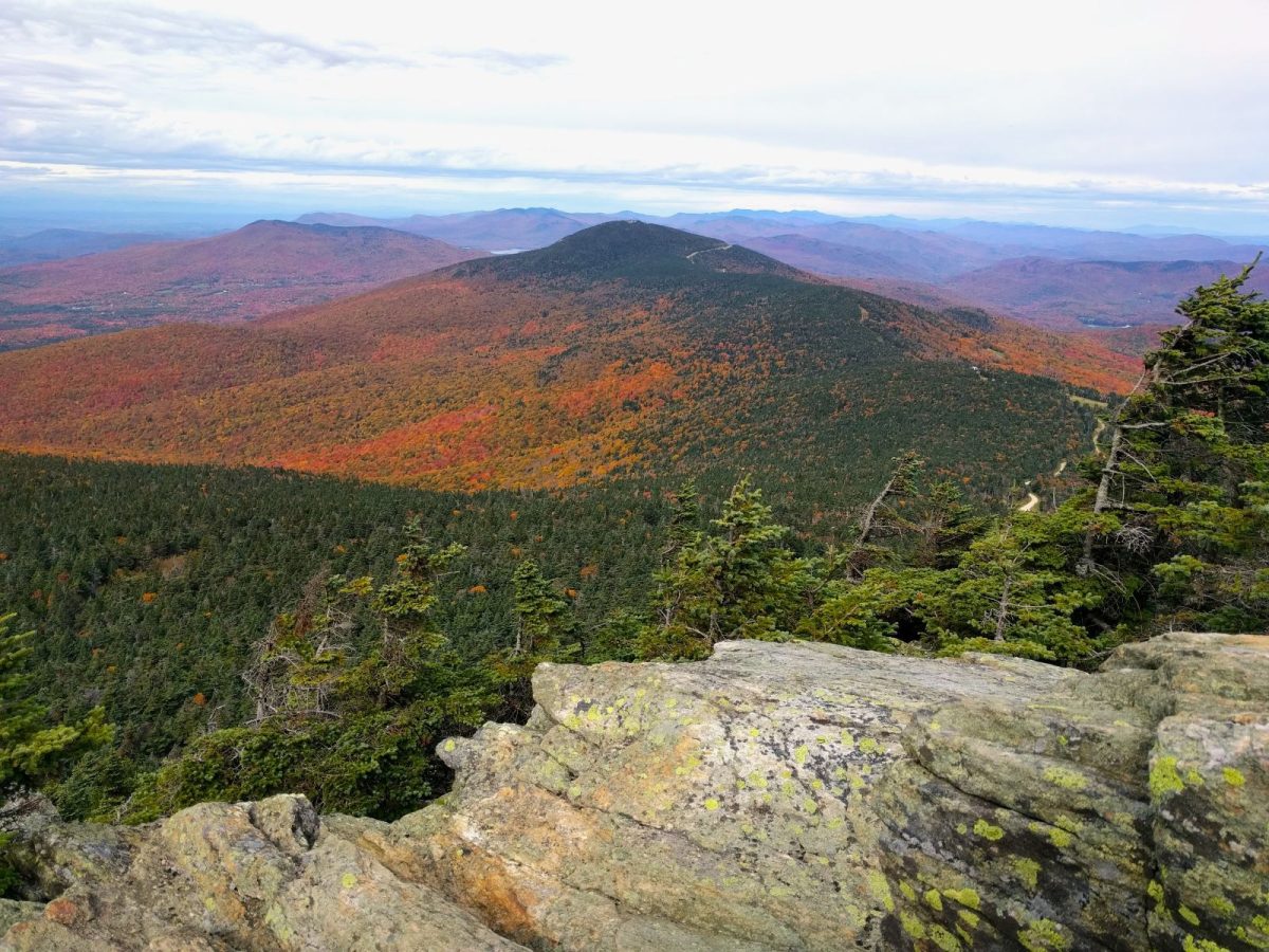 Rockface overlooking orange, green and blue mountains in Killington Vermont. 